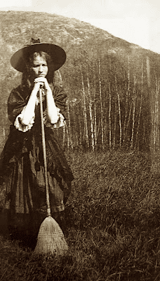 Edna St Vincent Millay dressed as a young witch under the Camden hills leans her chin on a broom handle